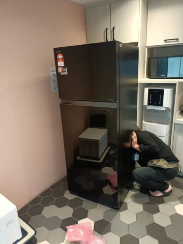 Refrigerator Repair 20 A person cleaning the condenser coils of a refrigerator to enhance cooling performance.