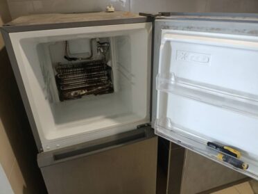 Refrigerator Repair 18 A professional technician repairing a refrigerator, checking components for proper functionality.